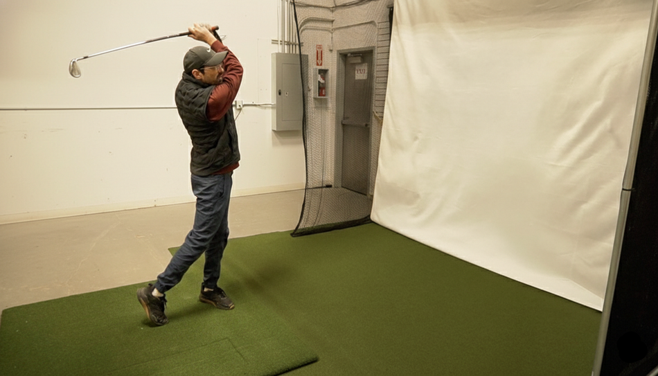 Person practicing golf swings in a indoor simulator